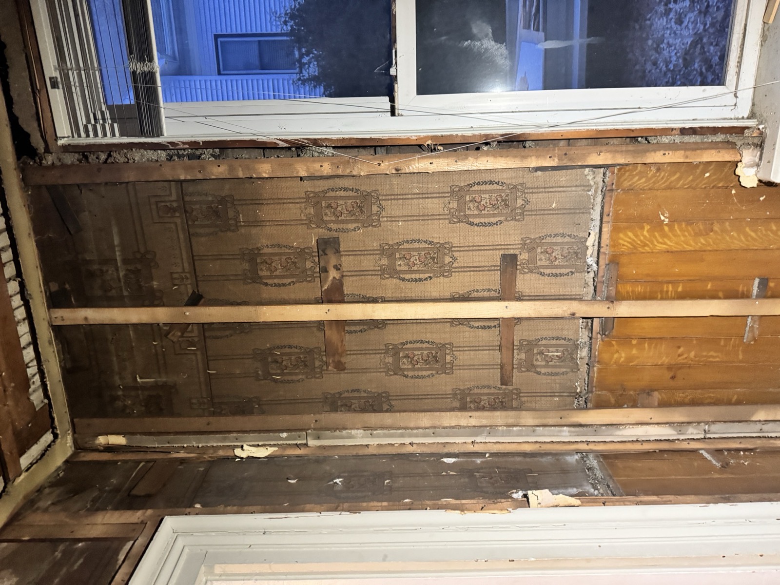 Opened wall showing lath and layers of old wallpaper